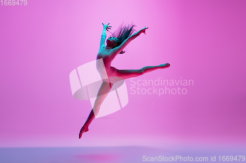 Image of Young and graceful ballet dancer isolated on pink studio background in neon light. Art, motion, action, flexibility, inspiration concept.