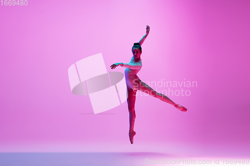 Image of Young and graceful ballet dancer isolated on pink studio background in neon light. Art, motion, action, flexibility, inspiration concept.