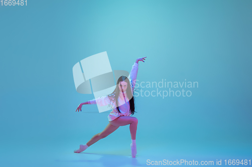 Image of Young and graceful ballet dancer isolated on blue studio background in neon light. Art, motion, action, flexibility, inspiration concept.