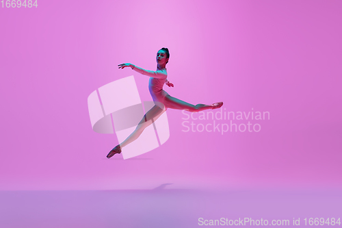 Image of Young and graceful ballet dancer isolated on pink studio background in neon light. Art, motion, action, flexibility, inspiration concept.