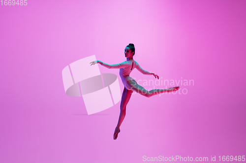 Image of Young and graceful ballet dancer isolated on pink studio background in neon light. Art, motion, action, flexibility, inspiration concept.