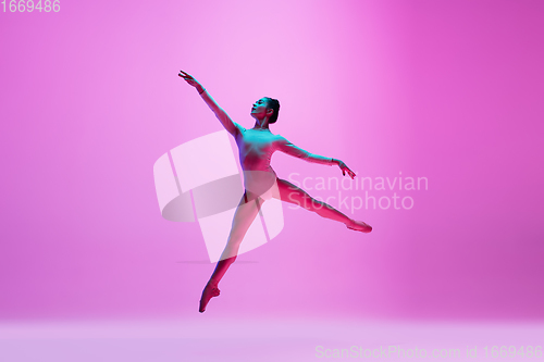 Image of Young and graceful ballet dancer isolated on pink studio background in neon light. Art, motion, action, flexibility, inspiration concept.