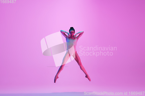Image of Young and graceful ballet dancer isolated on pink studio background in neon light. Art, motion, action, flexibility, inspiration concept.