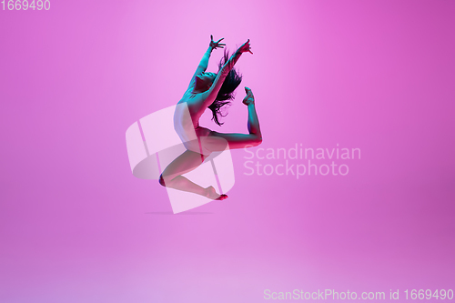 Image of Young and graceful ballet dancer isolated on pink studio background in neon light. Art, motion, action, flexibility, inspiration concept.