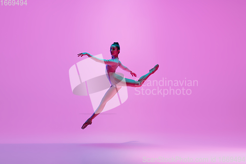 Image of Young and graceful ballet dancer isolated on pink studio background in neon light. Art, motion, action, flexibility, inspiration concept.