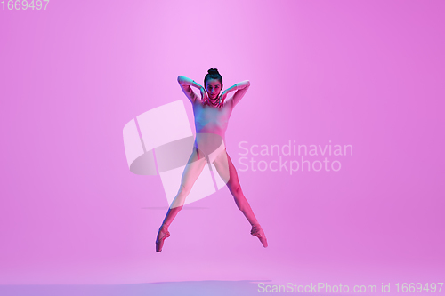 Image of Young and graceful ballet dancer isolated on pink studio background in neon light. Art, motion, action, flexibility, inspiration concept.
