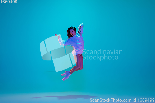 Image of Young and graceful ballet dancer isolated on blue studio background in neon light. Art, motion, action, flexibility, inspiration concept.