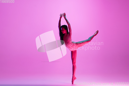 Image of Young and graceful ballet dancer isolated on pink studio background in neon light. Art, motion, action, flexibility, inspiration concept.