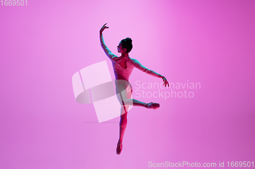 Image of Young and graceful ballet dancer isolated on pink studio background in neon light. Art, motion, action, flexibility, inspiration concept.