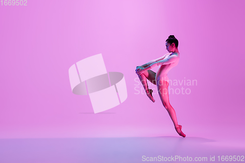 Image of Young and graceful ballet dancer isolated on pink studio background in neon light. Art, motion, action, flexibility, inspiration concept.