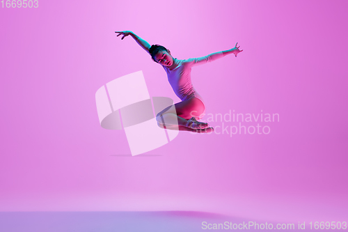 Image of Young and graceful ballet dancer isolated on pink studio background in neon light. Art, motion, action, flexibility, inspiration concept.