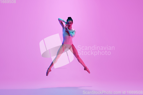 Image of Young and graceful ballet dancer isolated on pink studio background in neon light. Art, motion, action, flexibility, inspiration concept.