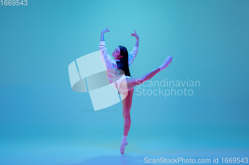 Image of Young and graceful ballet dancer isolated on blue studio background in neon light. Art, motion, action, flexibility, inspiration concept.