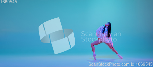 Image of Young and graceful ballet dancer isolated on blue studio background in neon light. Art, motion, action, flexibility, inspiration concept.