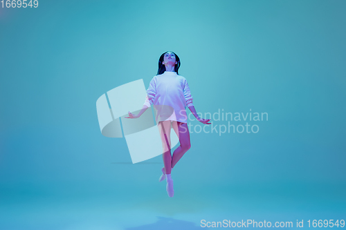 Image of Young and graceful ballet dancer isolated on blue studio background in neon light. Art, motion, action, flexibility, inspiration concept.