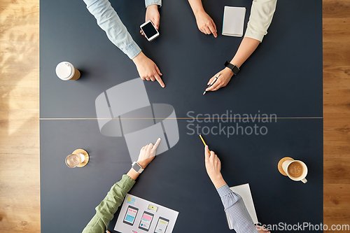 Image of business team pointing fingers to office table
