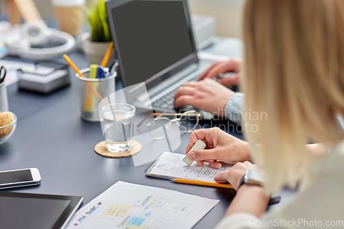 Image of woman with notebook working on ui design at office