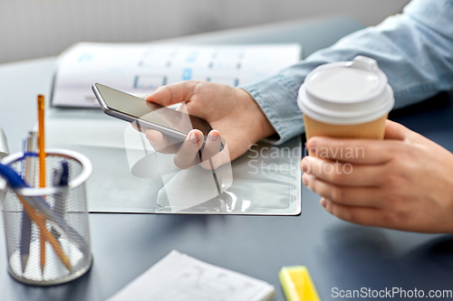 Image of woman with coffee using smartphone at office