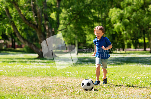 Image of happy little boy with ball playing soccer at park