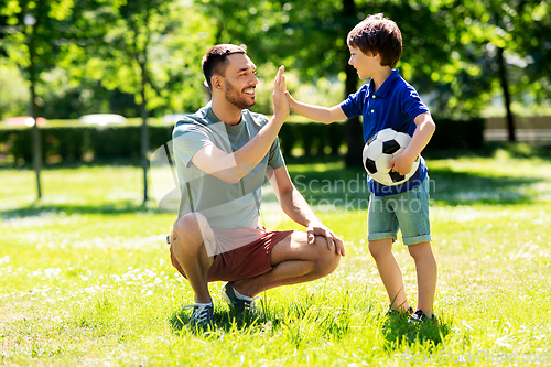 Image of father giving five to son with soccer ball at park