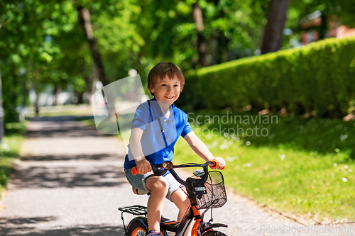 Image of happy little boy riding bicycle at summer park