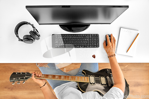 Image of young man with computer and guitar at table