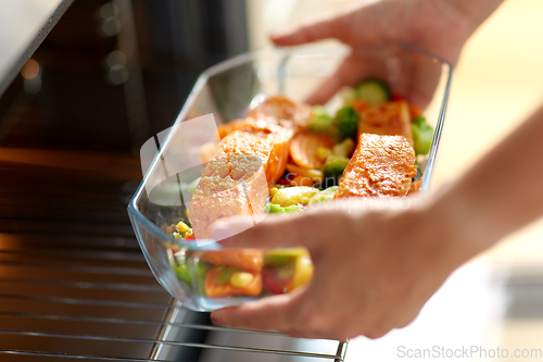 Image of woman cooking food in oven at home kitchen