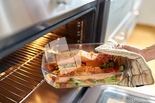 Image of woman cooking food in oven at home kitchen