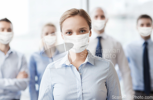 Image of businesswoman in mask with colleagues in office