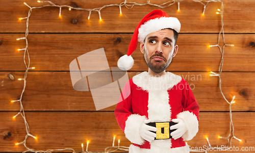 Image of sad santa over garland on wooden background