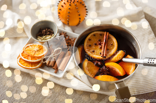 Image of pot with hot mulled wine, orange slices and spices