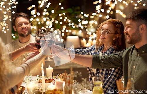 Image of happy friends drinking red wine at christmas party