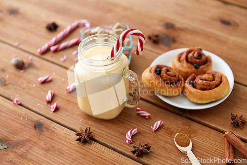 Image of eggnog with candy cane in mug and cinnamon buns