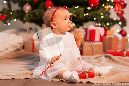 Image of baby girl at christmas tree with gifts at home