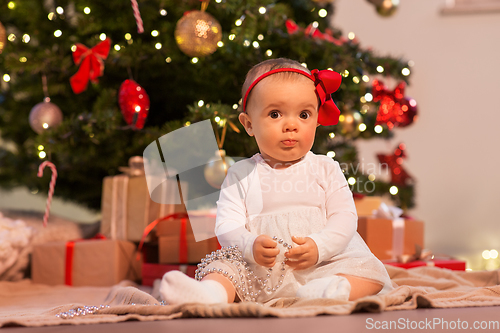 Image of baby girl at christmas tree with gifts at home