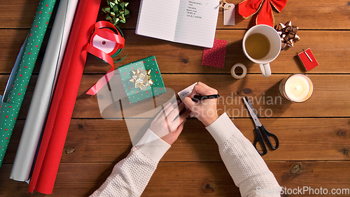 Image of hands attaching name tag to christmas gift