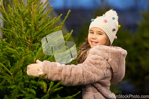 Image of little girl choosing christmas tree at market