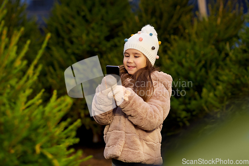 Image of girl with smartphone at christmas tree market