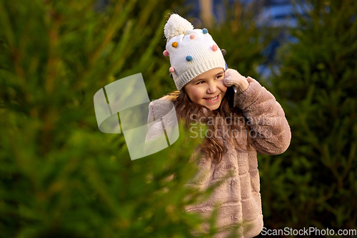 Image of girl calling on smartphone over christmas trees