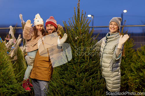 Image of happy family choosing christmas tree at market