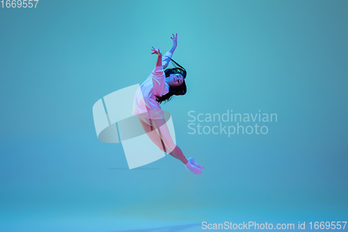 Image of Young and graceful ballet dancer isolated on blue studio background in neon light. Art, motion, action, flexibility, inspiration concept.