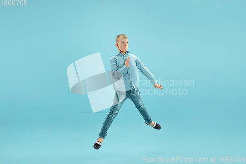 Image of Childhood and dream about big and famous future. Pretty little boy isolated on blue background