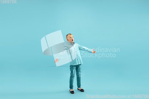 Image of Childhood and dream about big and famous future. Pretty little boy isolated on blue background