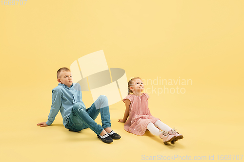 Image of Childhood and dream about big and famous future. Boy and girl isolated on yellow studio background