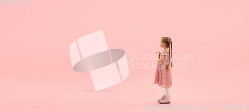 Image of Childhood and dream about big and famous future. Pretty longhair girl isolated on coral pink background