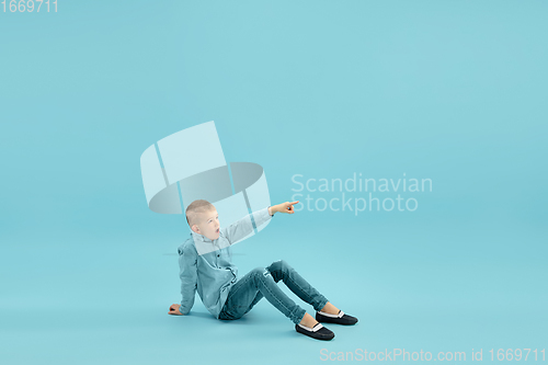 Image of Childhood and dream about big and famous future. Pretty little boy isolated on blue background