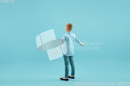 Image of Childhood and dream about big and famous future. Pretty little boy isolated on blue background