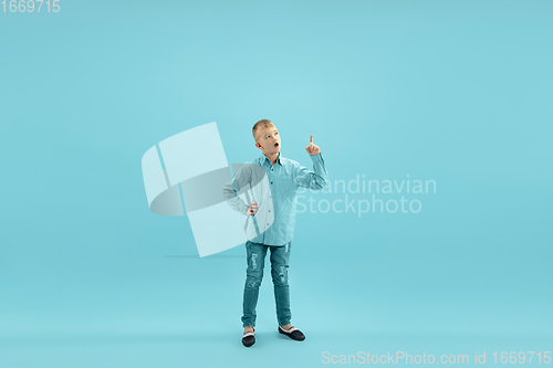 Image of Childhood and dream about big and famous future. Pretty little boy isolated on blue background