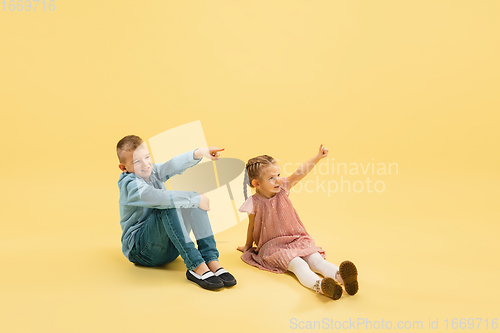 Image of Childhood and dream about big and famous future. Boy and girl isolated on yellow studio background