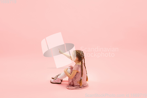 Image of Childhood and dream about big and famous future. Pretty longhair girl isolated on coral pink background